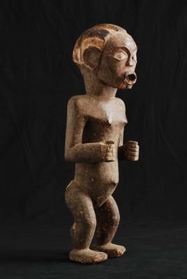 une statue en bois représentant un homme avec une cigarette à la bouche