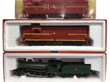 deux wagons rouges et verts dans une boîte posée sur une surface blanche