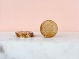 two gold coins sitting on top of a marble counter next to a pink wall