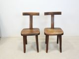 two wooden chairs sitting next to each other in a room