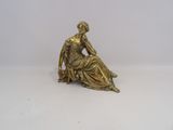 statue en or représentant une femme assise par terre, les mains posées sur les genoux