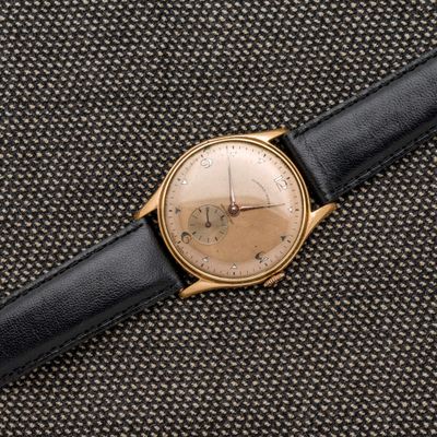 un gros plan d'une montre posée sur un tissu noir