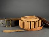 two leather belts and a leather knife on a gray surface