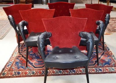Plusieurs fauteuils en cuir noir sont disposés en cercle sur un tapis rouge