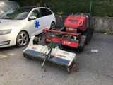 deux tondeuses à gazon sur un parking, à côté d'une voiture