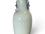 a white vase with blue beads on it on a white surface