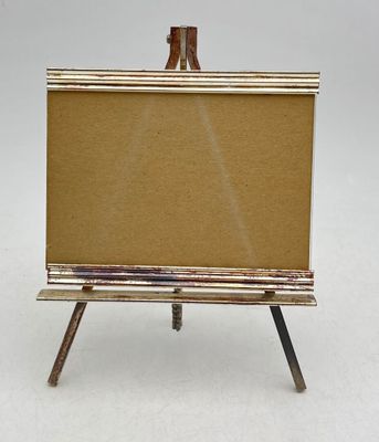 an easel with a canvas on it sitting on a white surface