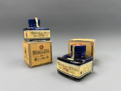 two bottles of ink sitting next to each other on a table