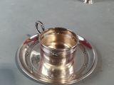 a silver cup and saucer sitting on a table