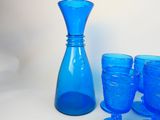 a blue glass vase and a set of glasses on a table