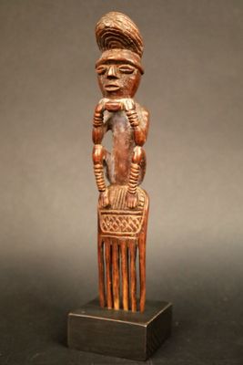 un gros plan sur une sculpture en bois représentant une personne assise sur une chaise