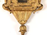 a gold clock hanging on the wall with a picture on it