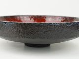 a black and red bowl sitting on a white surface