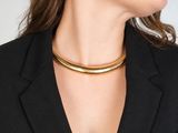 une femme portant un blazer noir et un collier ras-du-cou doré