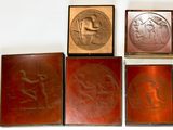 quatre types différents de plaques métalliques exposées sur un fond blanc