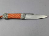 a small knife with an orange handle on a table