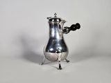 une cafetière ancienne en argent avec une poignée noire sur fond blanc