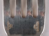 a silver fork with a metal handle on a white surface