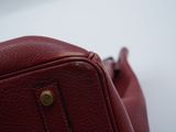 a close up of a red purse on a white surface