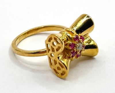 bague en or jaune ornée de pierres roses et d'un nœud sur le dessus