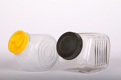 deux bocaux en plastique vides avec leurs couvercles, posés sur une surface blanche