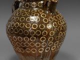 un vase marron orné de cercles, posé sur une table
