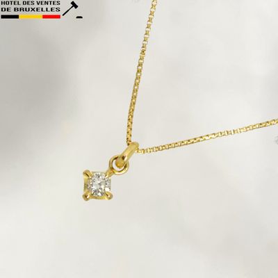 a close up of a gold necklace with a diamond on it
