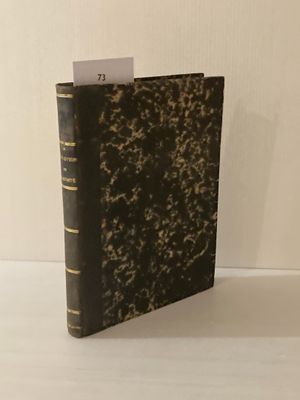 un vieux livre posé sur une table blanche à côté d'un mur blanc