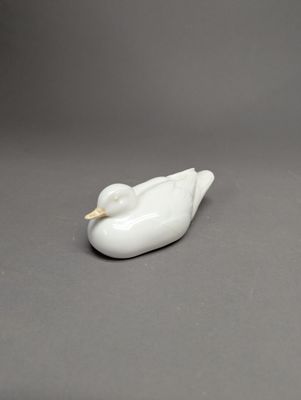 figurine de canard en porcelaine blanche posée sur une surface grise