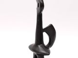 black sculpture of a woman holding a vase on top of a table