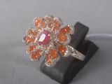 an image of a ring with a pink stone surrounded by orange stones