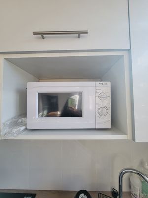 un micro-ondes blanc posé sur une étagère au-dessus d'un évier