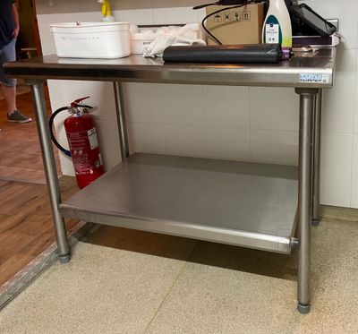 une table en acier inoxydable dans une cuisine équipée d'un extincteur