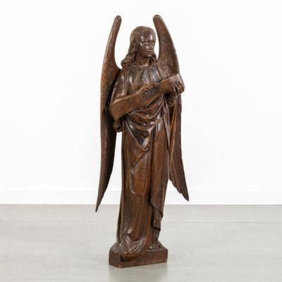 a wooden statue of an angel holding a cross