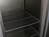 an empty refrigerator with a metal shelf in the corner