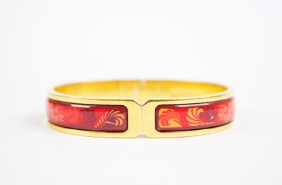 un gros plan d'un bracelet rouge et doré posé sur une surface blanche