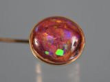 a close up of a pink and green fire oplite in a gold ring