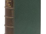un vieux livre à la couverture verte posé sur une surface blanche