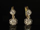 a pair of diamond earrings on a black surface