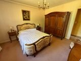 une chambre avec un lit, une commode et un lustre