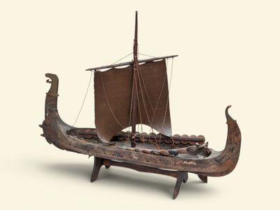 un bateau en bois avec une voile marron posé sur une table