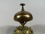 a brass plate with a bell on top of it on a white surface