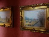 paintings on the wall of a bathroom with a toilet and a sink