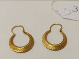deux paires de boucles d'oreilles en or posées sur une surface blanche, avec une étiquette de prix