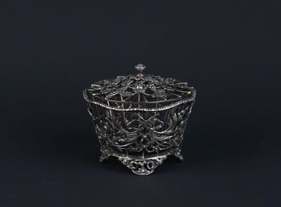 an antique silver plated bowl with a handle on a black background