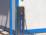 un bâtiment bleu et blanc équipé d'une borne de recharge électrique sur le trottoir