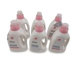 Quatre biberons de lait en poudre pour bébé sont alignés sur une surface blanche