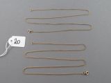 a group of gold necklaces and a tag on a gray surface