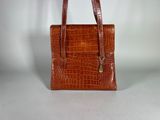 brown alligator skin handbag on white background