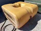 un réservoir d'eau jaune posé à même le sol à côté d'un conteneur vert